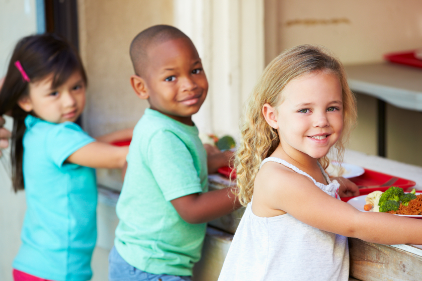 Children smiling for camera during school lunch